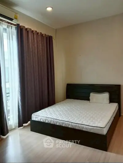 Cozy bedroom with large window and modern bed frame, perfect for relaxation.