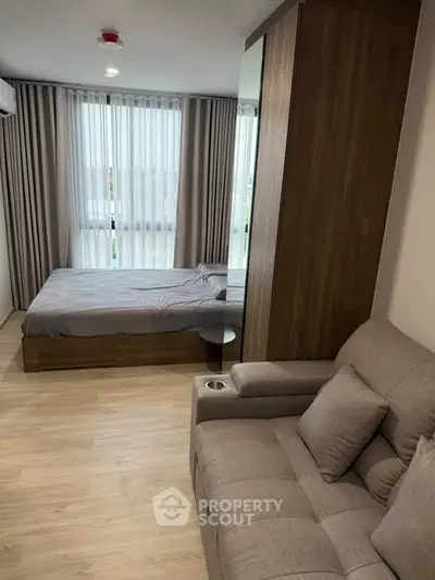 Modern bedroom with cozy seating and large windows in a stylish apartment.