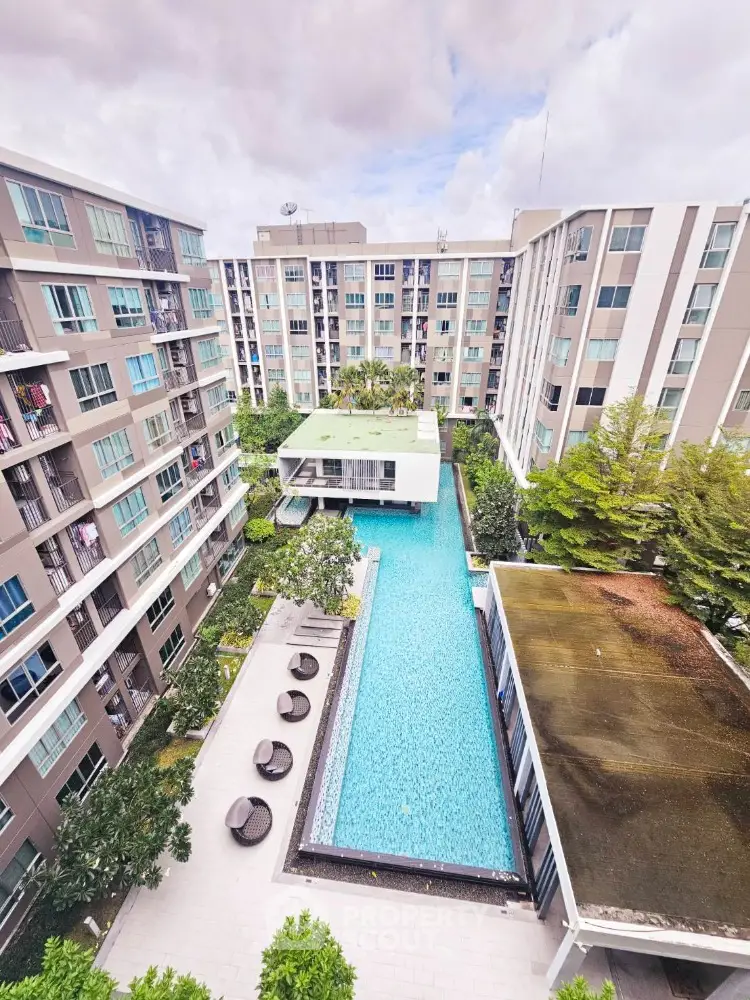 Modern condominium complex with central swimming pool and lush greenery.