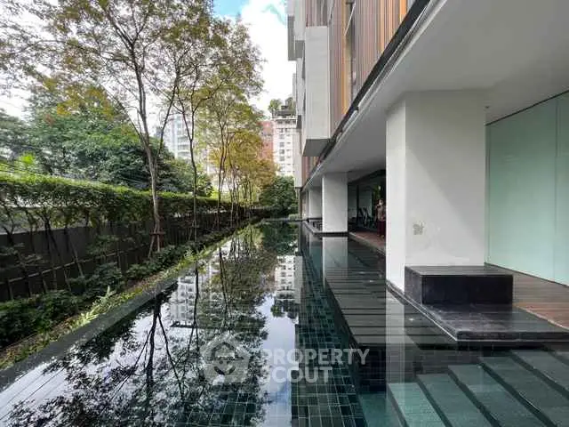 Luxurious modern building with serene pool and lush greenery