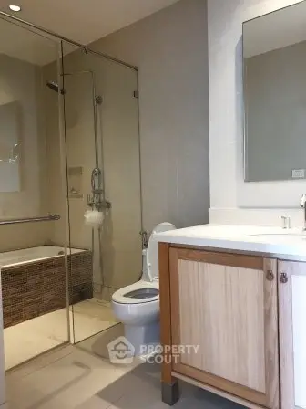 Modern bathroom with glass shower and wooden vanity in upscale apartment.