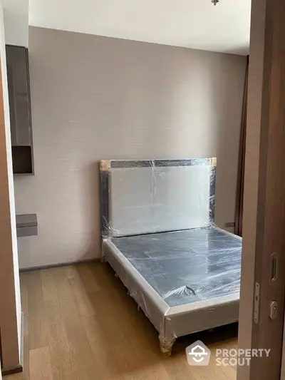 Modern bedroom with new bed frame and wooden flooring in a stylish apartment.