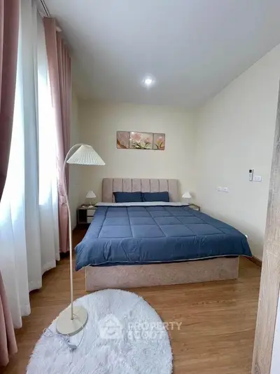 Cozy bedroom with modern decor and natural light, featuring a plush bed and elegant lighting.
