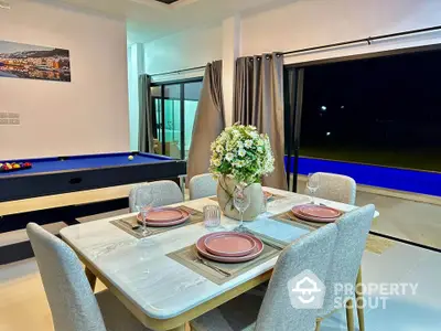 Luxurious dining area with pool table and night pool view