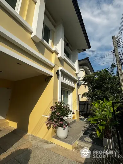 Charming yellow exterior of modern home with lush garden and inviting entrance