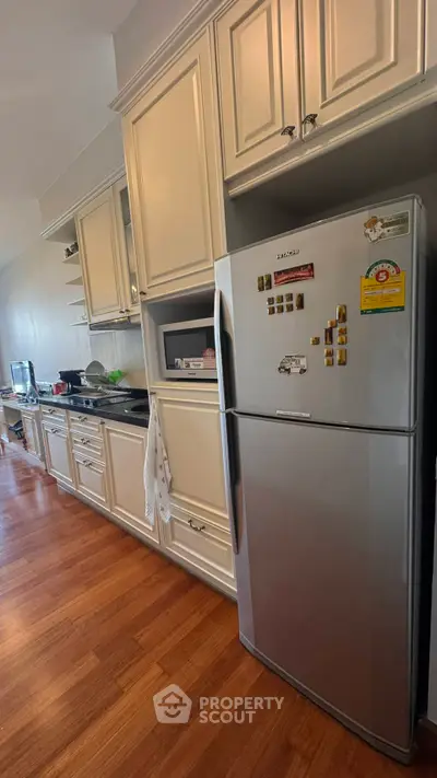 Modern kitchen with sleek appliances and wooden flooring, featuring a spacious fridge and elegant cabinetry.