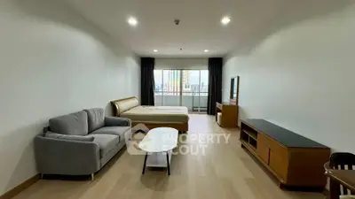 Spacious studio apartment with modern furnishings and city view balcony.