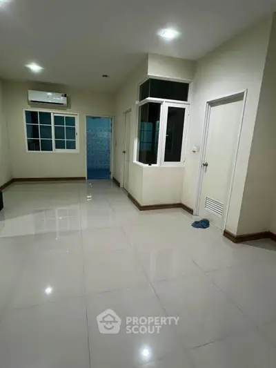 Spacious empty room with tiled flooring and air conditioning, ideal for customization.