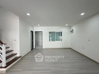 Spacious modern living room with sleek flooring and recessed lighting, perfect for contemporary living.
