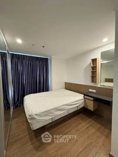 Modern bedroom with wooden flooring and large mirrored wardrobe