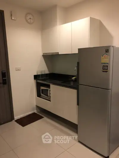 Modern kitchen with sleek cabinets and stainless steel fridge in cozy apartment.