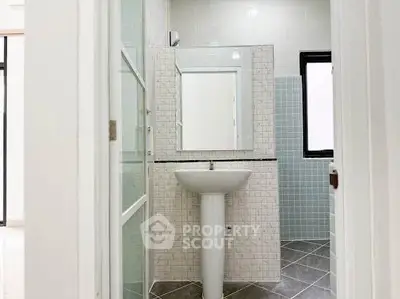 Modern bathroom with pedestal sink and tiled walls in a bright, minimalist design.