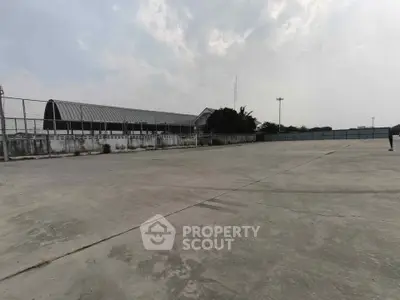 Expansive outdoor concrete area with industrial building backdrop, ideal for commercial use.