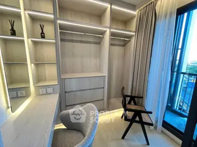 Modern bedroom with built-in wardrobe and balcony access, featuring elegant chairs and natural light.