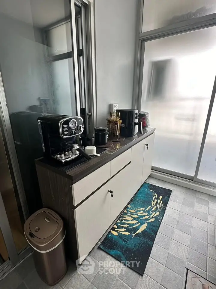 Modern kitchen corner with coffee machine and sleek cabinetry in bright apartment.