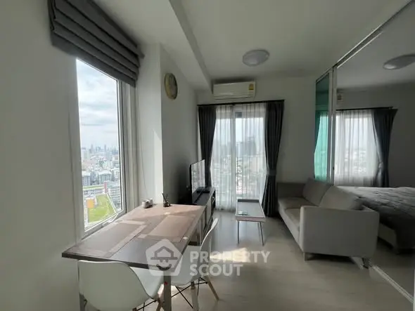 Modern living room with city view, featuring sleek furniture and abundant natural light.