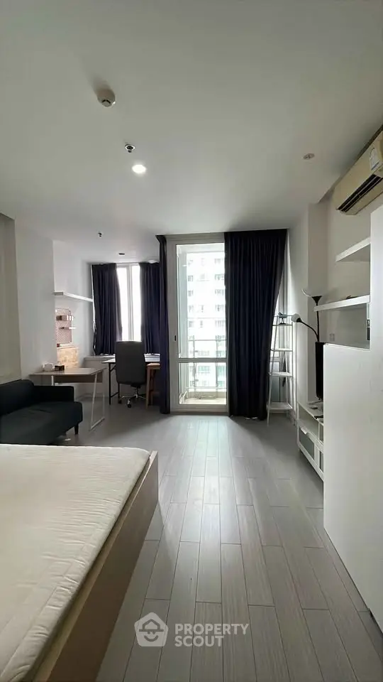 Modern studio apartment with sleek design and city view, featuring a cozy living area and workspace.