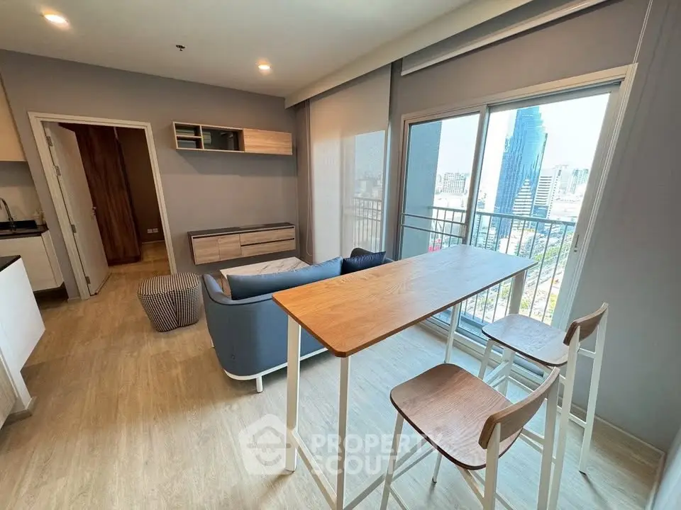 Modern living room with city view, featuring sleek furniture and large windows for natural light.