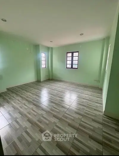 Spacious empty room with tiled flooring and green walls, perfect for customization.