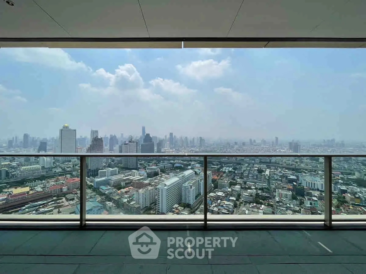 Stunning cityscape view from a high-rise balcony with glass railing, showcasing urban skyline.