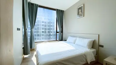 Modern bedroom with large window and city view, featuring elegant decor and natural light.