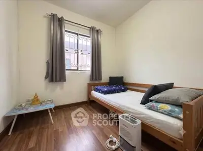 Cozy bedroom with wooden flooring, single bed, and natural light from window.