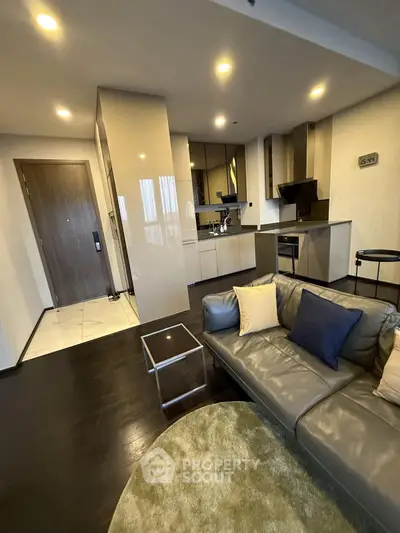 Modern living room with sleek kitchen in open layout, featuring stylish furniture and contemporary design.