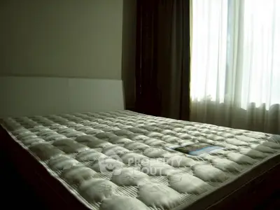 Spacious bedroom with large window and comfortable mattress, perfect for relaxation.