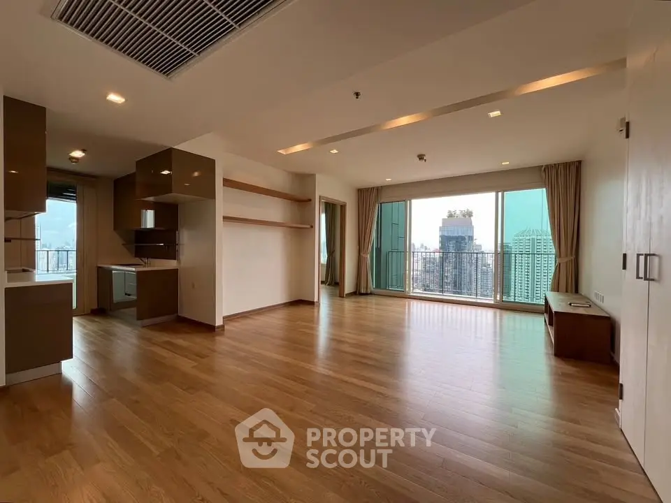 Spacious modern living room with wooden flooring and city view balcony in luxury apartment.