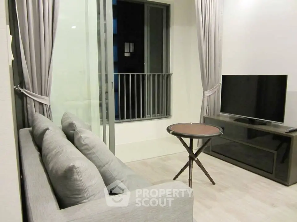 Modern living room with sleek TV setup and cozy sofa near balcony.