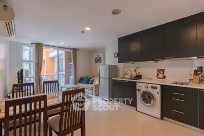 Modern open-plan kitchen and living area with sleek black cabinets and natural light.