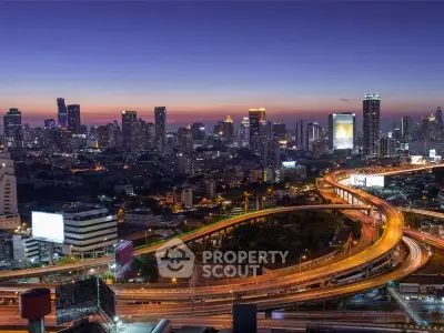 Stunning cityscape view with illuminated skyline and winding highways at dusk.