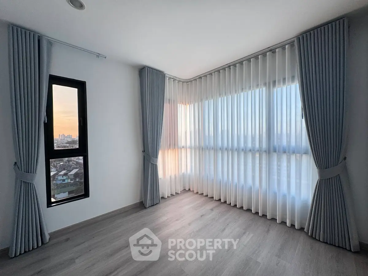 Spacious corner unit with large windows and elegant curtains offering a serene city view.