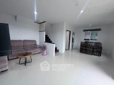 Spacious modern living room with staircase and dining area in a bright open layout.