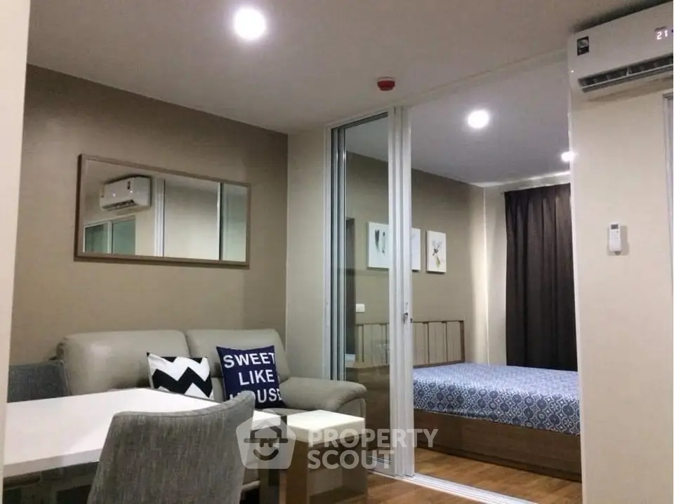 Modern studio apartment with cozy living area and bedroom, featuring sleek furniture and warm lighting.