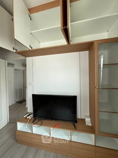 Modern living room with sleek wooden cabinetry and mounted TV