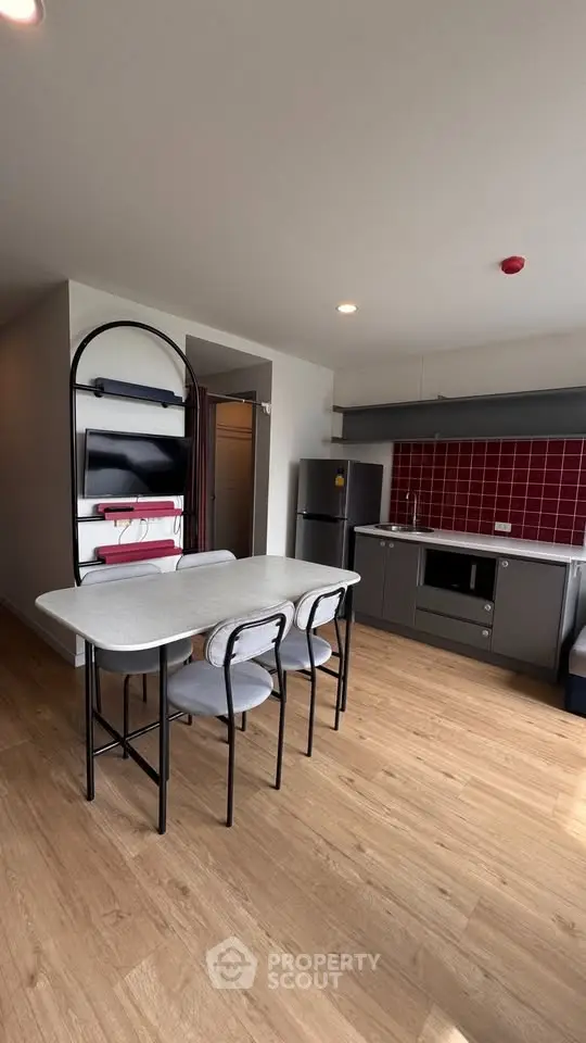 Modern kitchen with sleek design, featuring a dining table and stylish red backsplash.