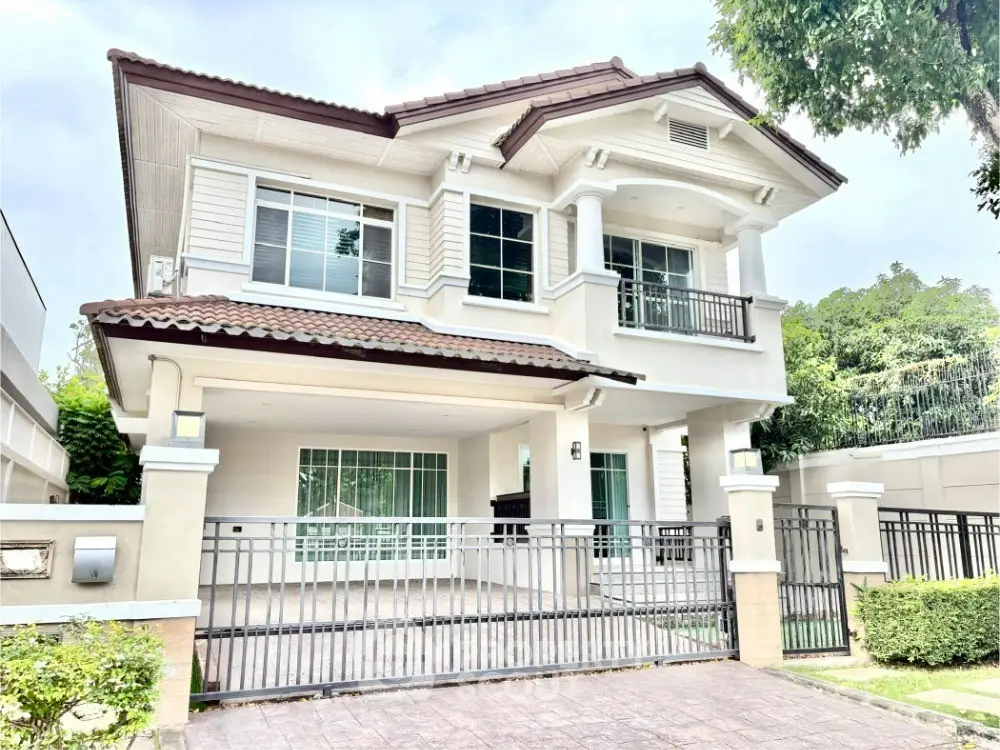 Stunning two-story modern house with gated entrance and lush greenery.