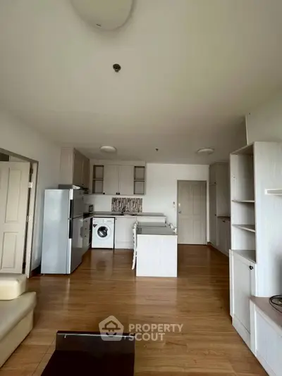 Spacious open-layout kitchen with modern appliances and wooden flooring in a cozy apartment.