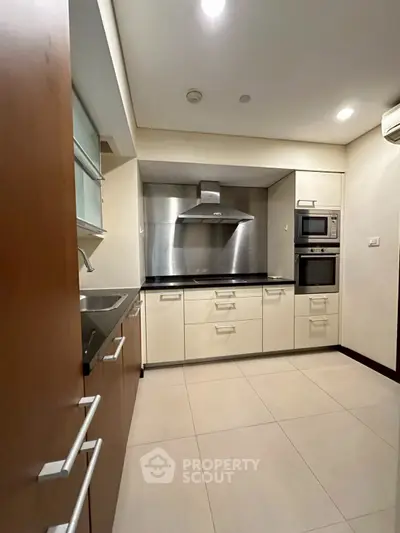 Modern kitchen with sleek cabinetry and built-in appliances, featuring a stainless steel range hood.