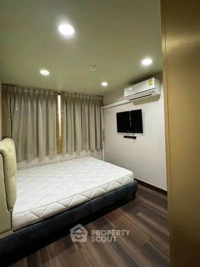 Modern bedroom with sleek design, featuring a comfortable bed, wall-mounted TV, and air conditioning.