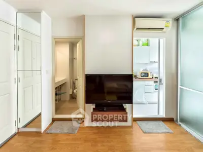 Modern living room with TV, hardwood floors, and kitchen view