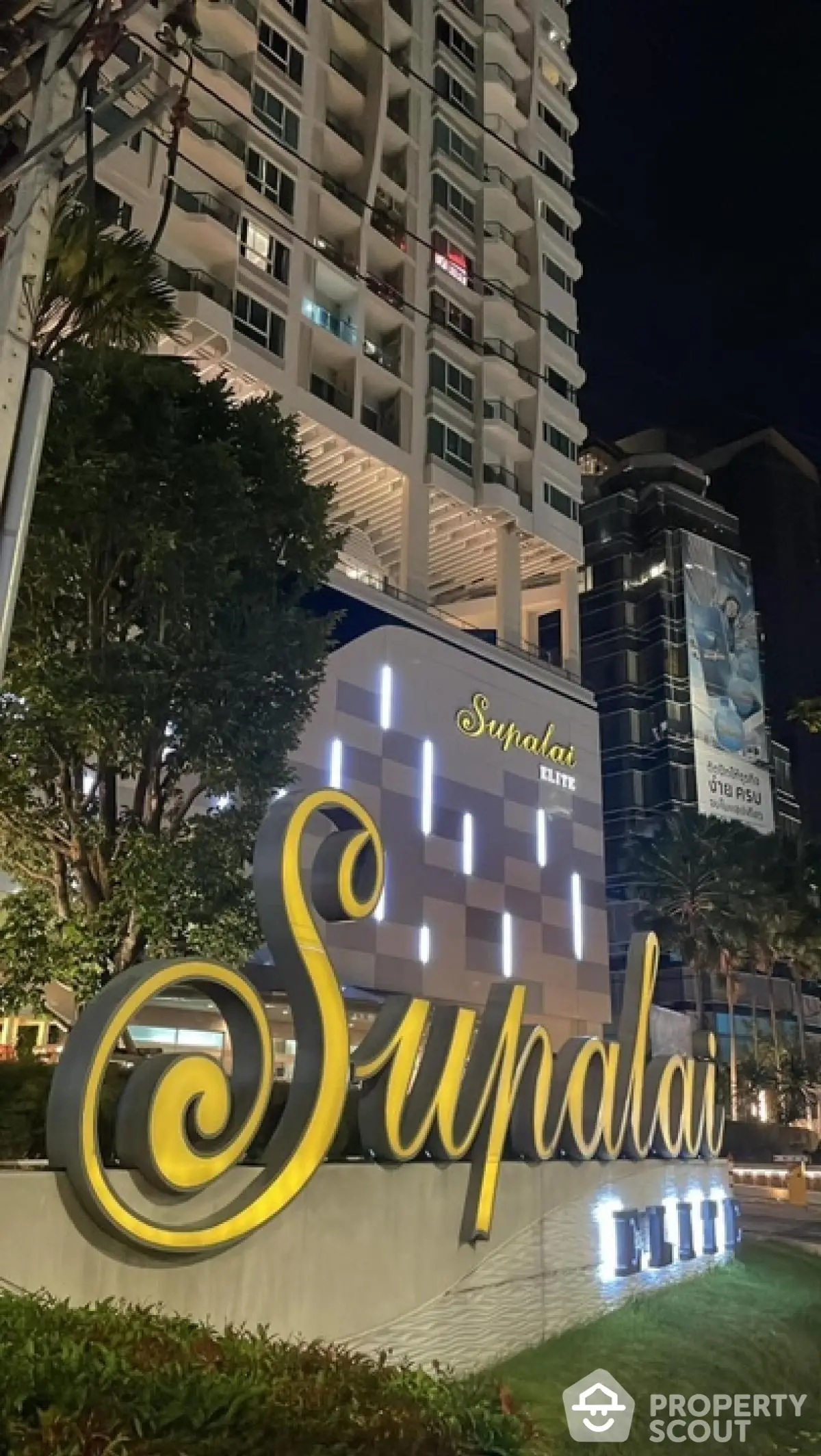 Luxurious Supalai Elite building exterior at night with illuminated signage and modern architecture.