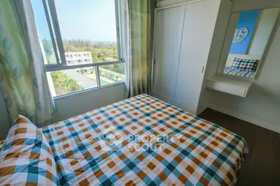 Cozy bedroom with large window offering scenic view and stylish checkered bedding.