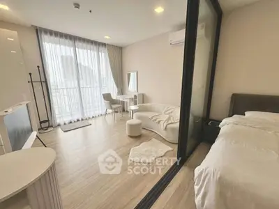 Modern studio apartment with open layout, featuring a cozy living area and bedroom, large windows, and stylish decor.