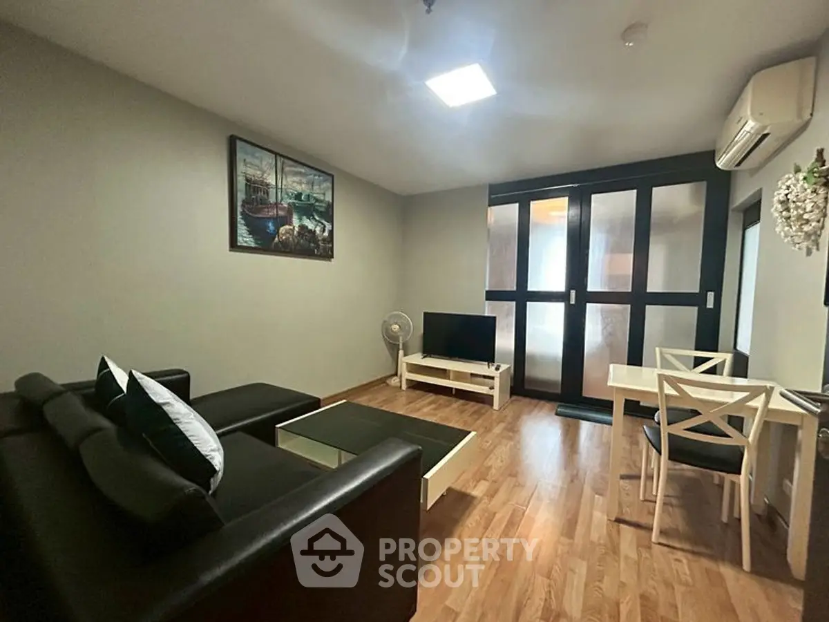 Modern living room with sleek black sofa, wooden flooring, and stylish decor.