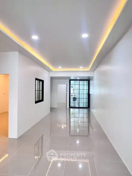 Spacious modern living room with sleek tile flooring and ambient ceiling lighting.