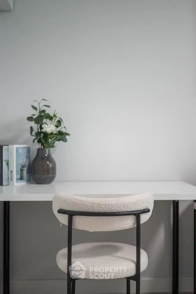 Minimalist study area with modern chair and desk, featuring a decorative plant and books for a serene workspace.