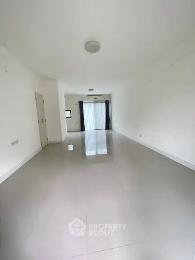 Spacious empty living room with glossy tiled floors and large window.
