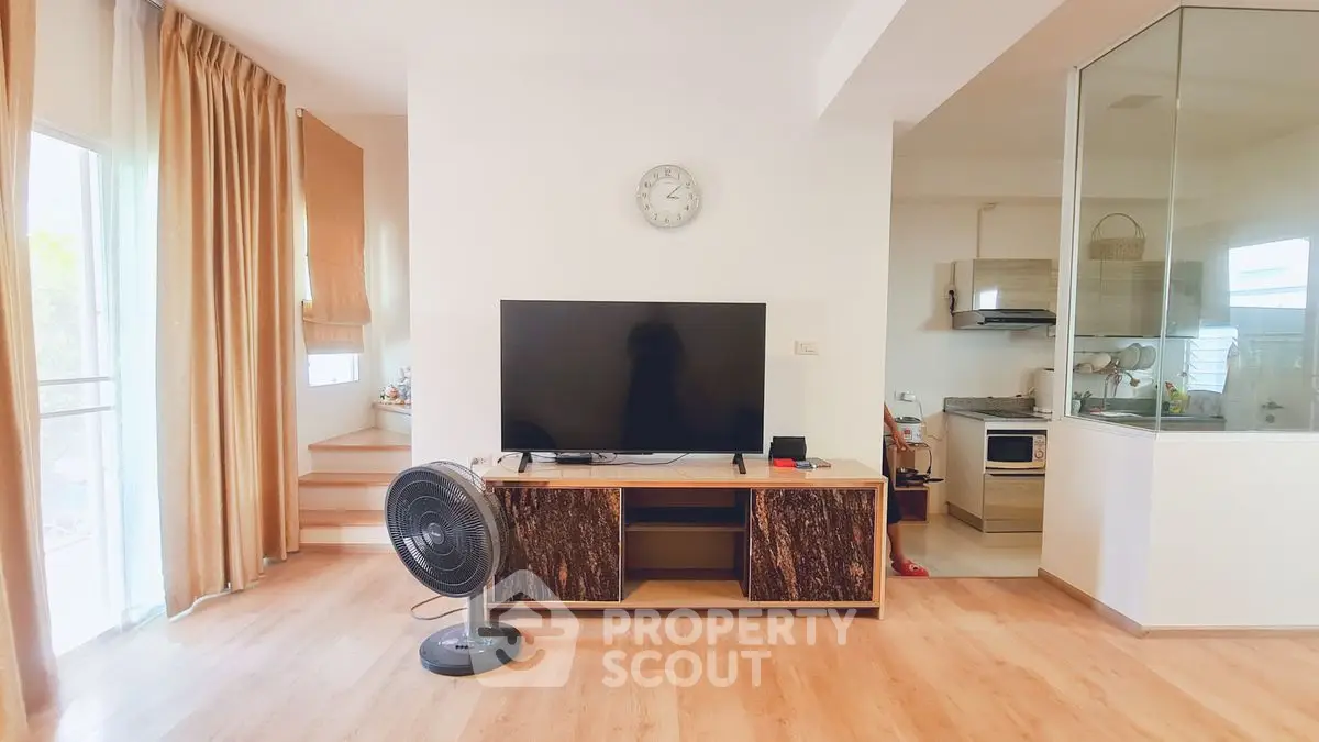 Modern living room with TV, fan, and stylish wooden flooring